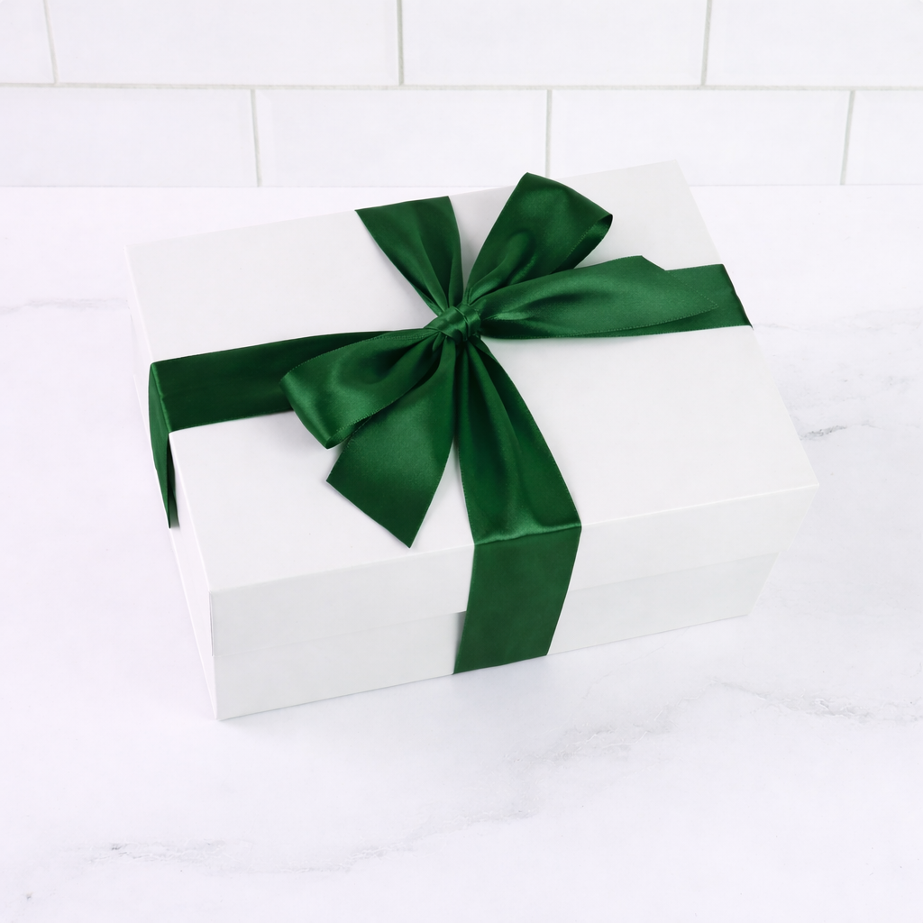 White gift box with a green ribbon on a white tiled background