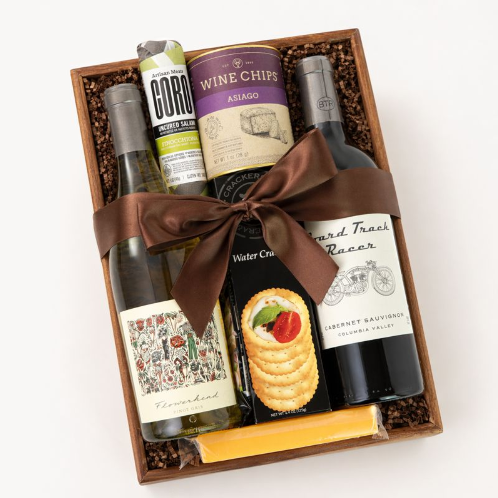Gift basket with wine, cheese, and snacks on a white background
