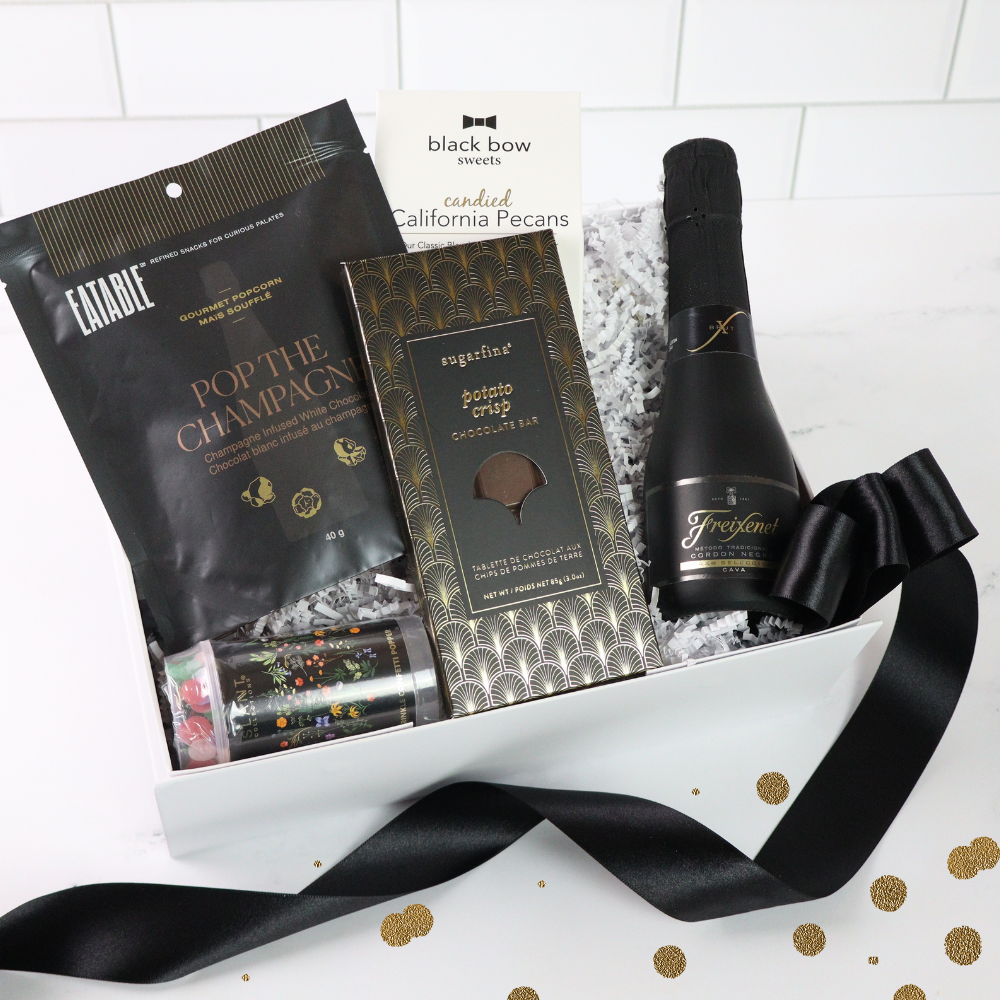 Gift basket with chocolate, champagne, and snacks on a white background