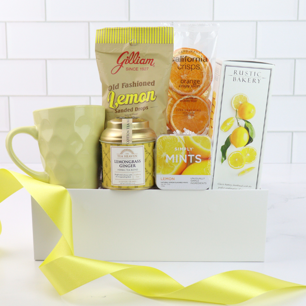 Gift basket with lemon-themed items including a mug, tea, candy, and snacks on a white background.