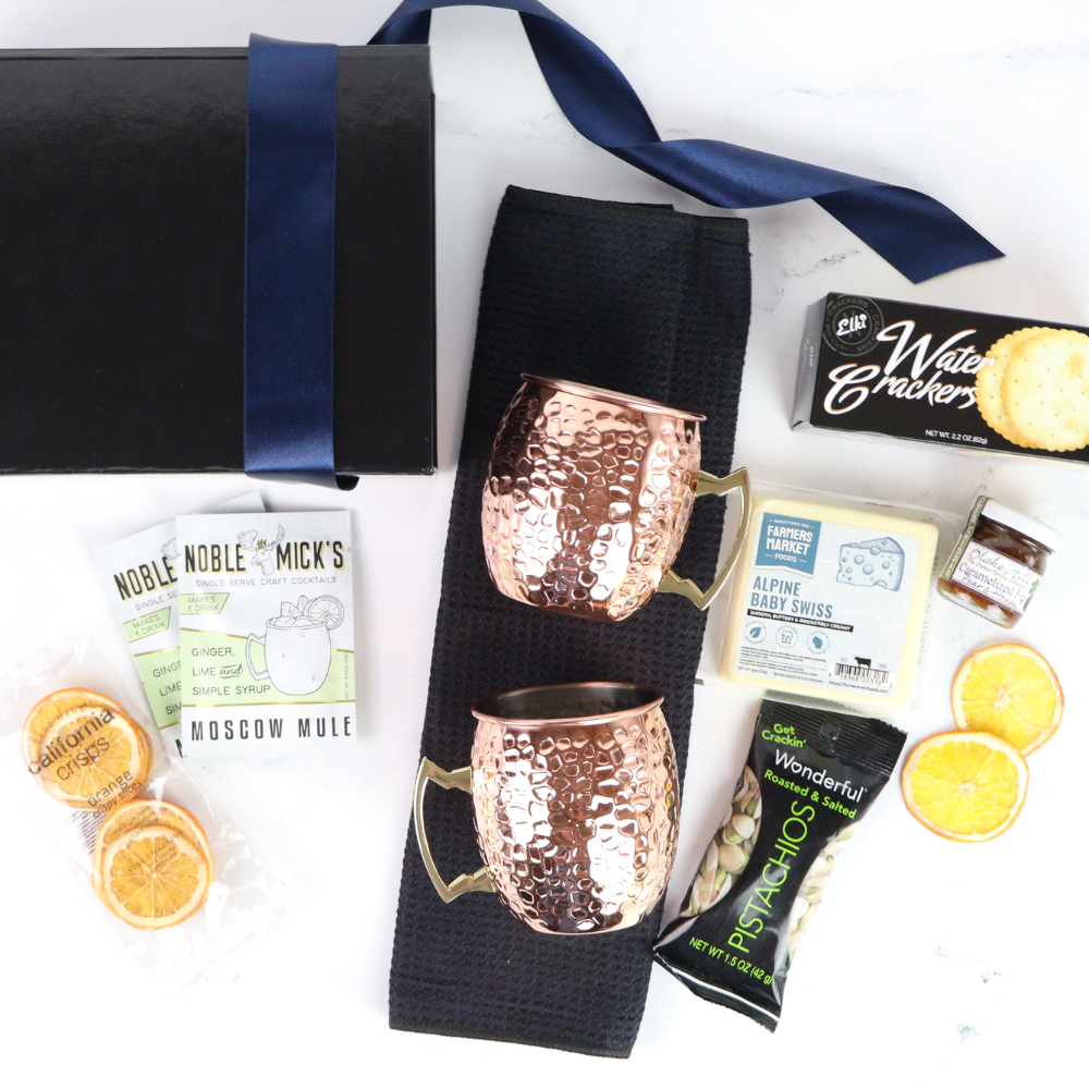 Gift basket with travel-themed items including a mug, cookies, and books on a white background