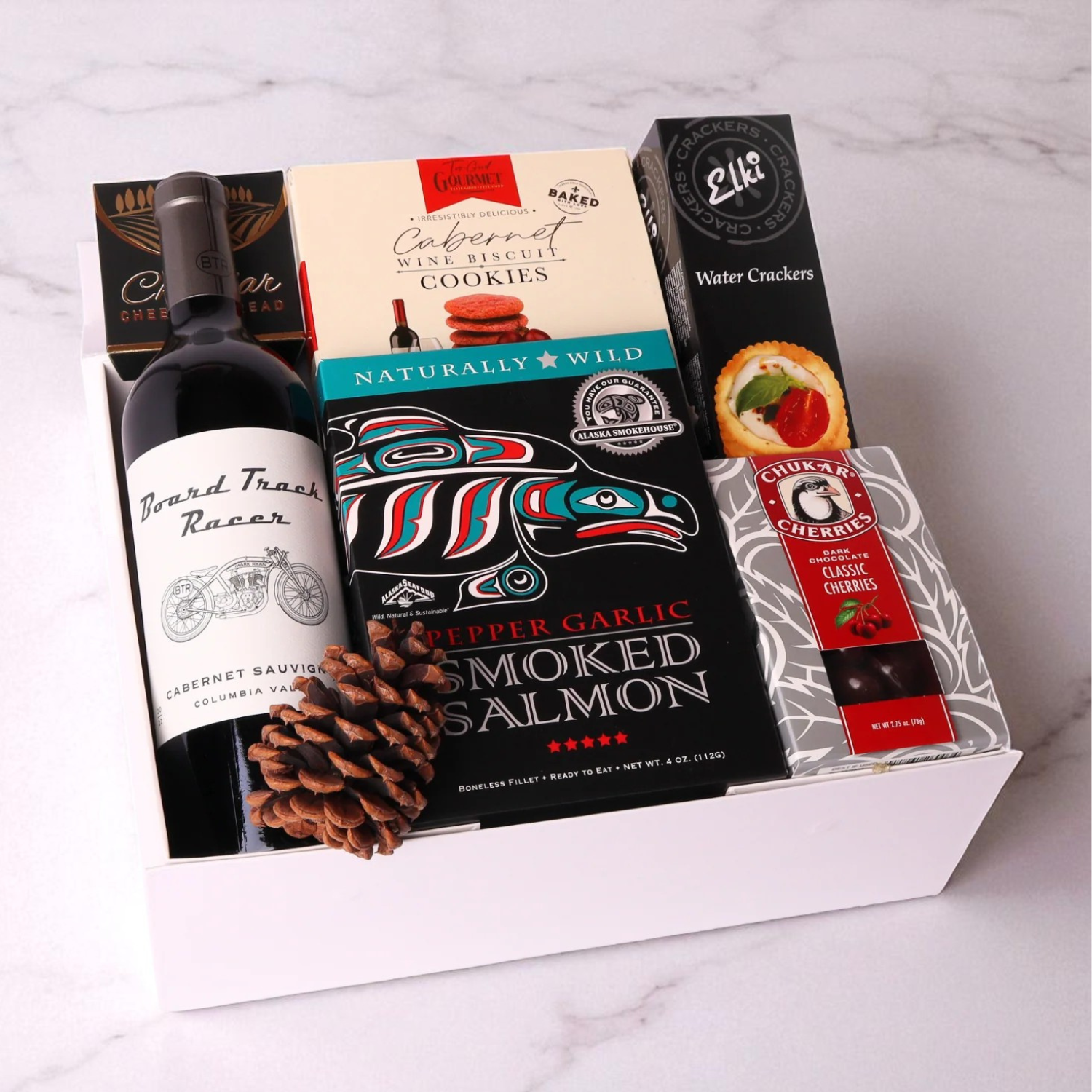 Gift basket with mark ryan wine, cookies, smoked salmon, and crackers on a marble surface