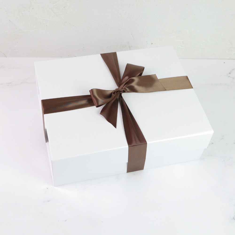 White gift box with a brown ribbon on a light gray background