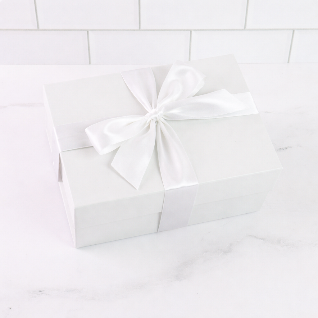 White gift box with a bow on a white tiled background