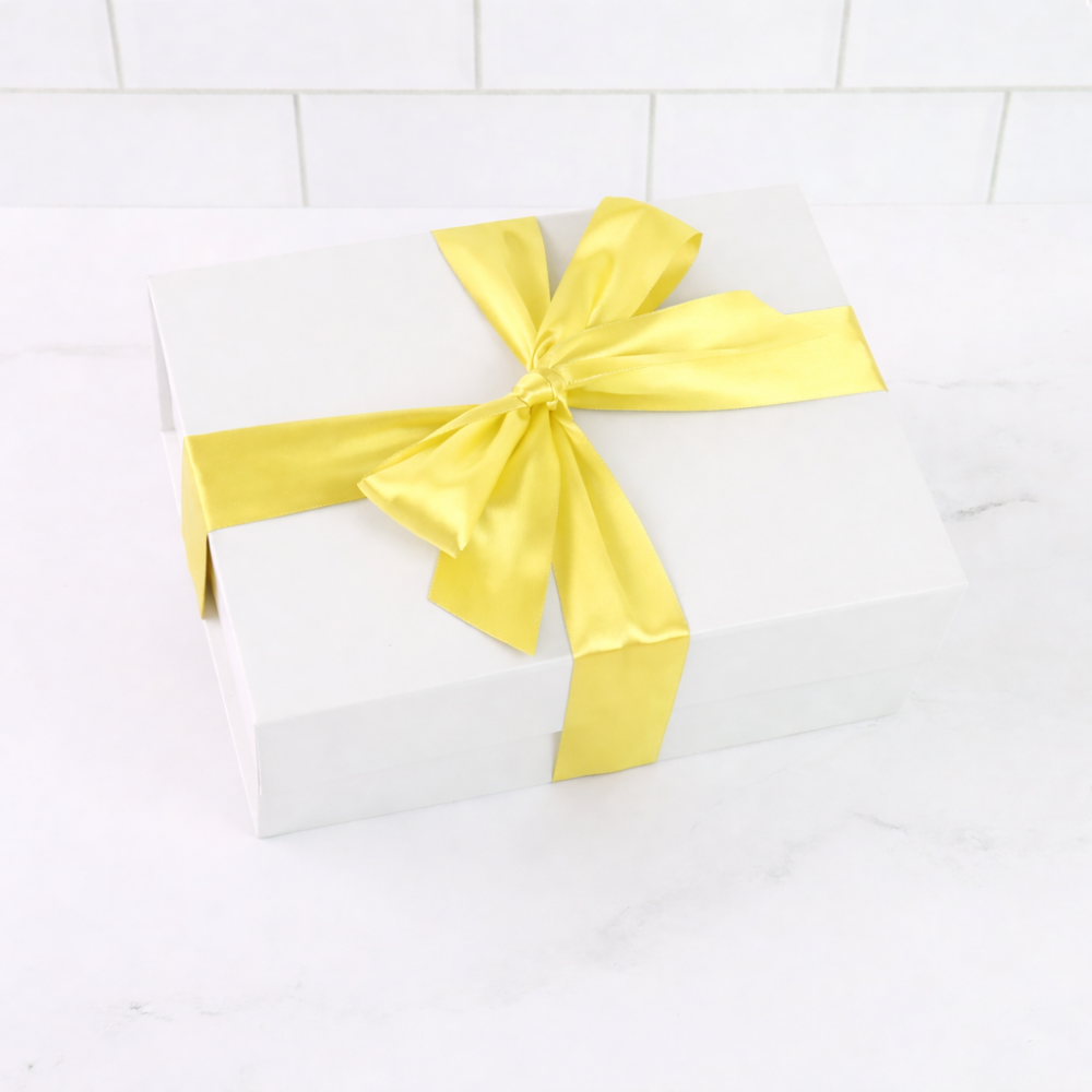 White box with a yellow ribbon on a white tiled background
